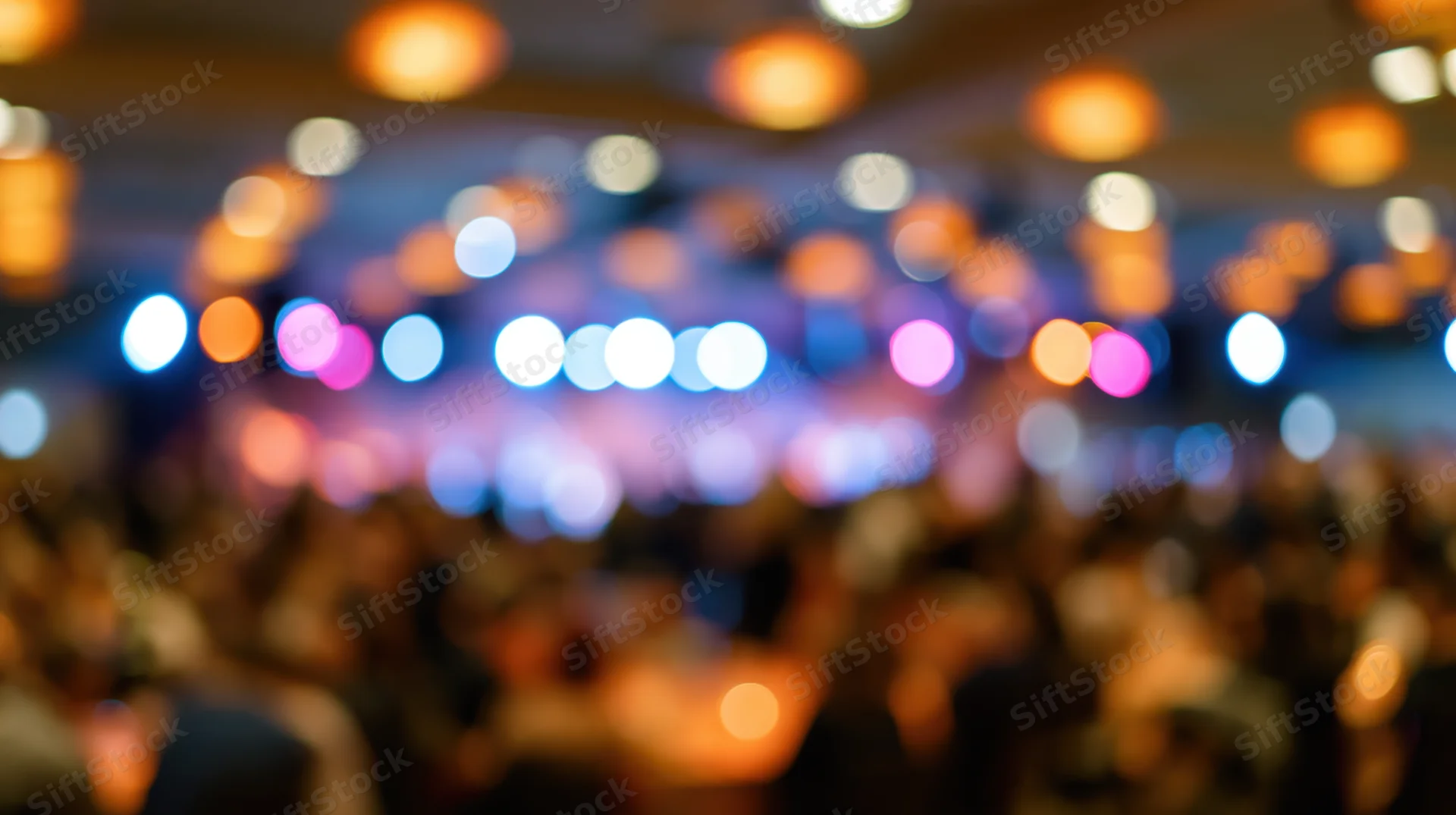 Defocused interior of a crowded event venue with colorful bokeh lights on the ceiling