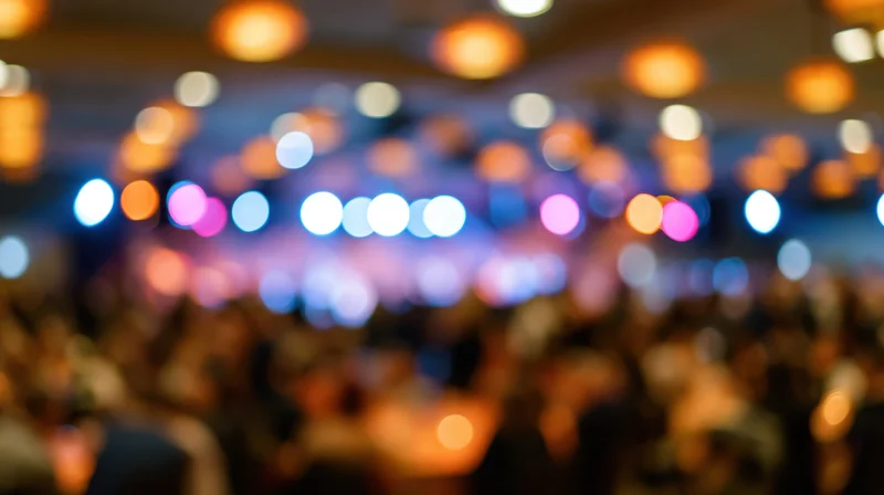 Defocused interior of a crowded event venue with colorful bokeh lights on the ceiling