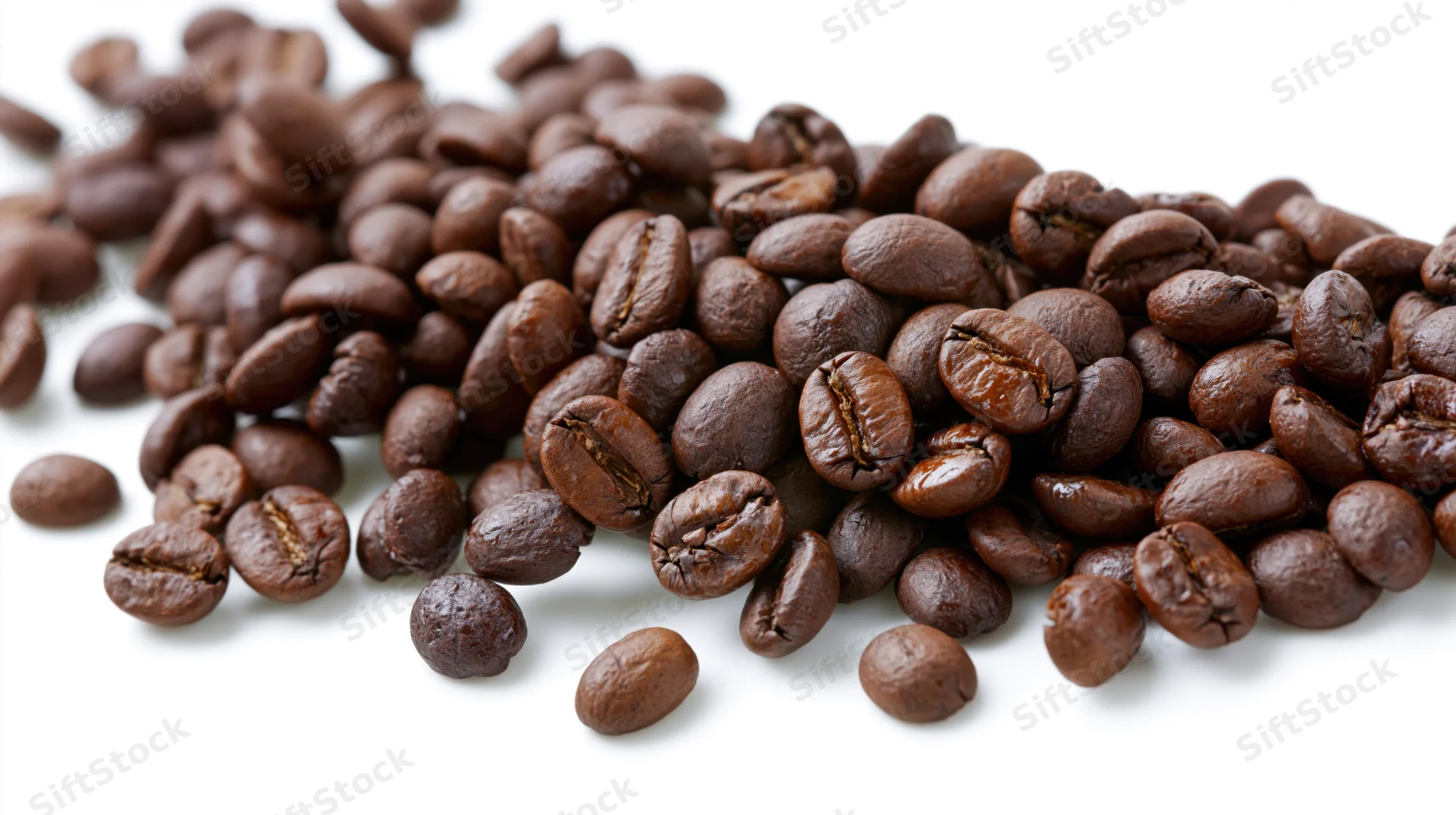 Roasted coffee beans scattered across a white surface