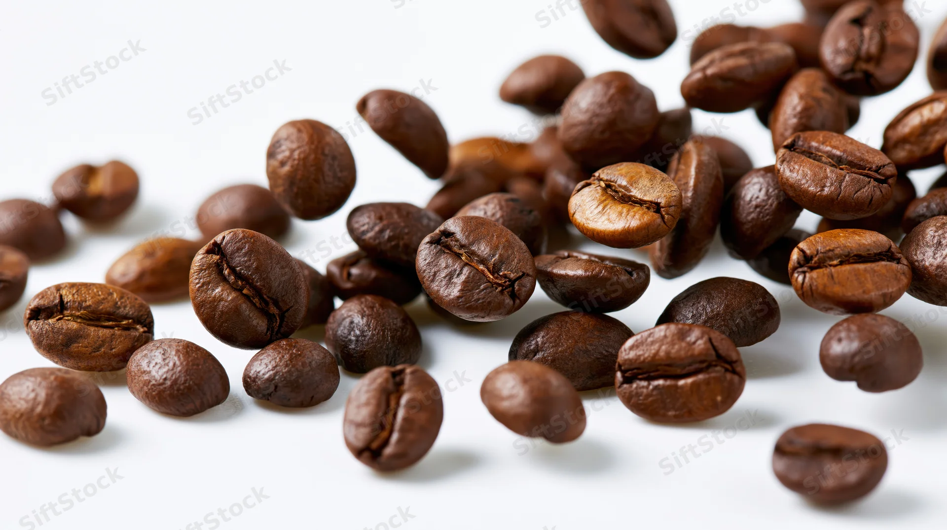 Roasted coffee beans frozen midair scattering on white background