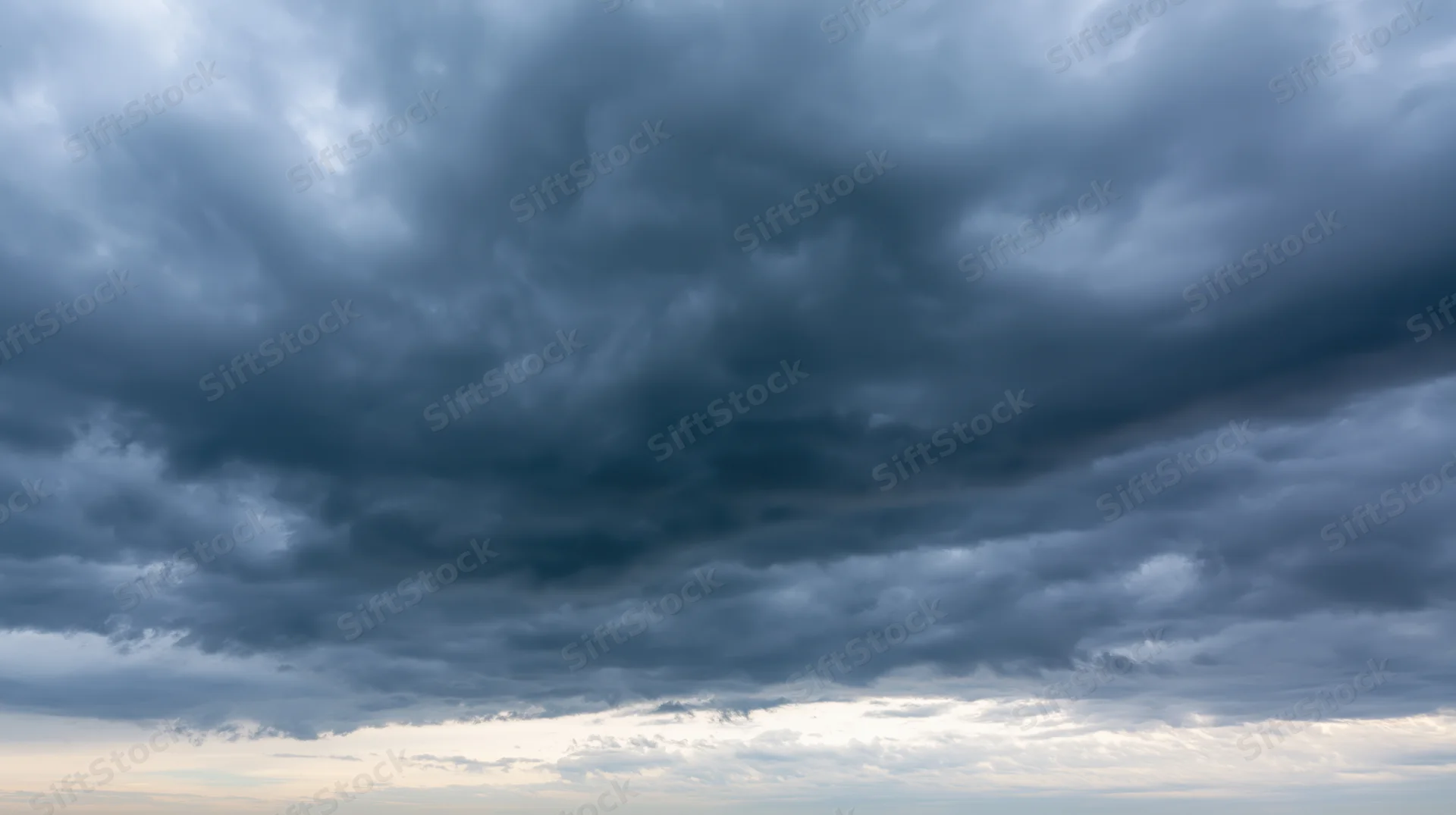 Dramatic stormy sky filled with dark cumulonimbus clouds at twilight