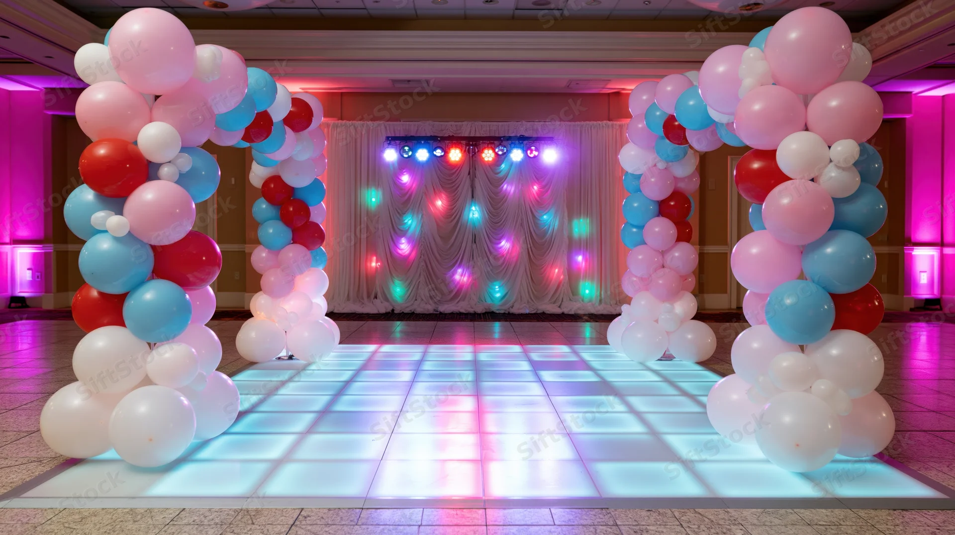 Illuminated dance floor framed by balloon arches in a decorated event venue