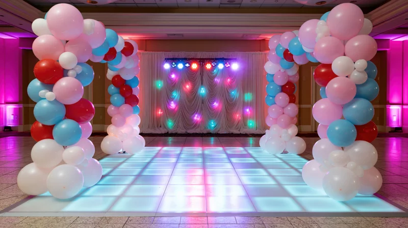 Illuminated dance floor framed by balloon arches in a decorated event venue
