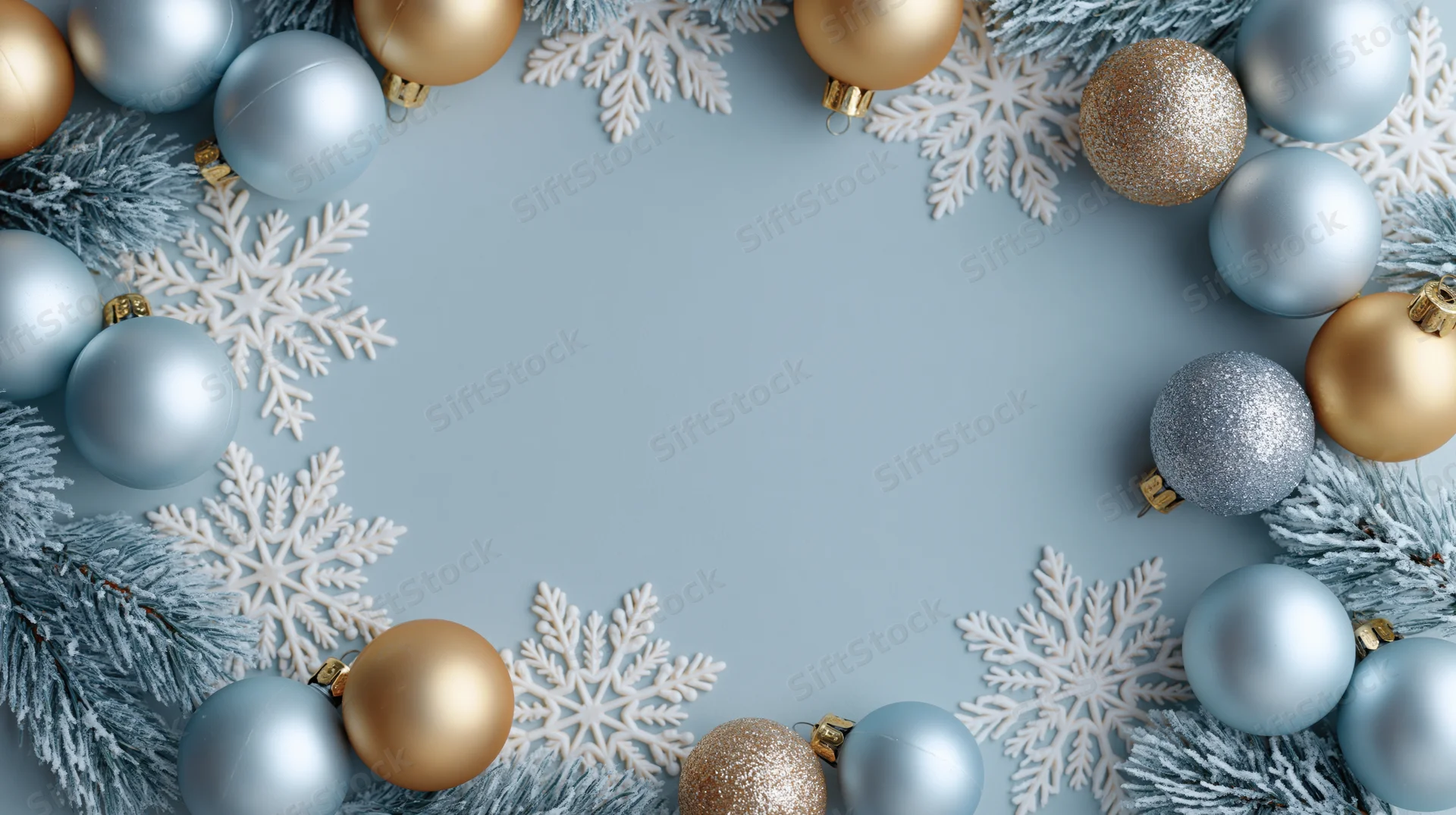 Christmas ornaments and snowflakes arranged in a frame around a blue background with copyspace