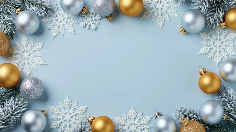 Silver and gold christmas ornaments with snowflakes and pine branches arranged in a border on a light blue background