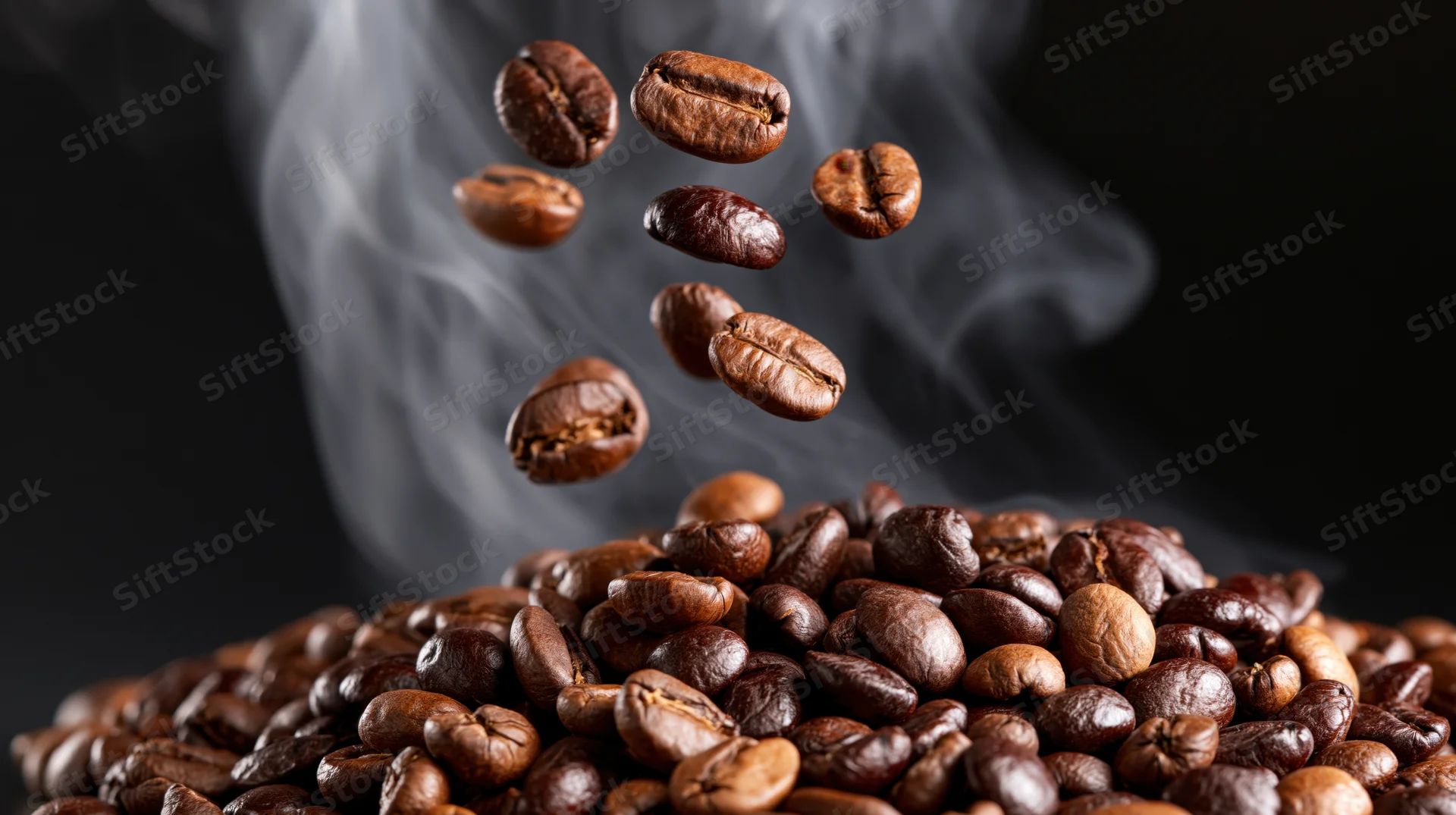 Roasted coffee beans falling and floating above a steaming pile on dark background