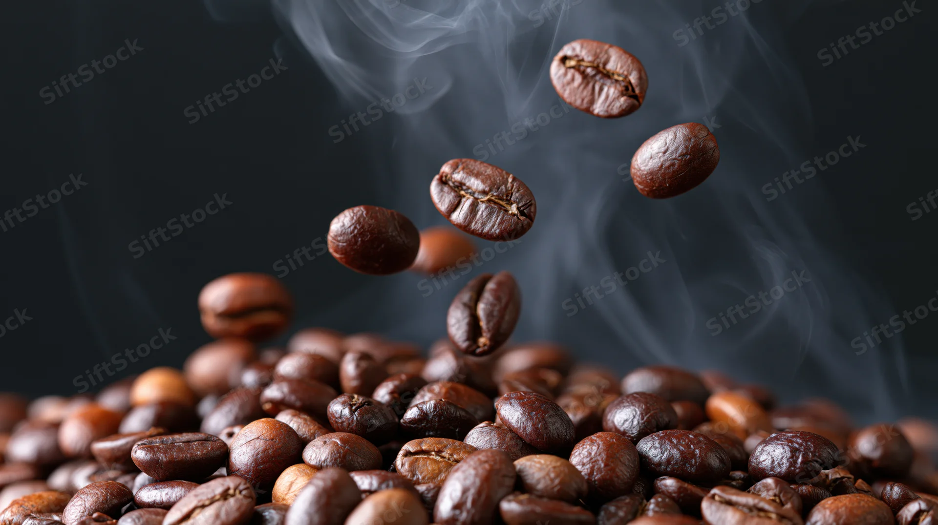 Roasted coffee beans falling in mid-air above a pile with rising steam against a dark background