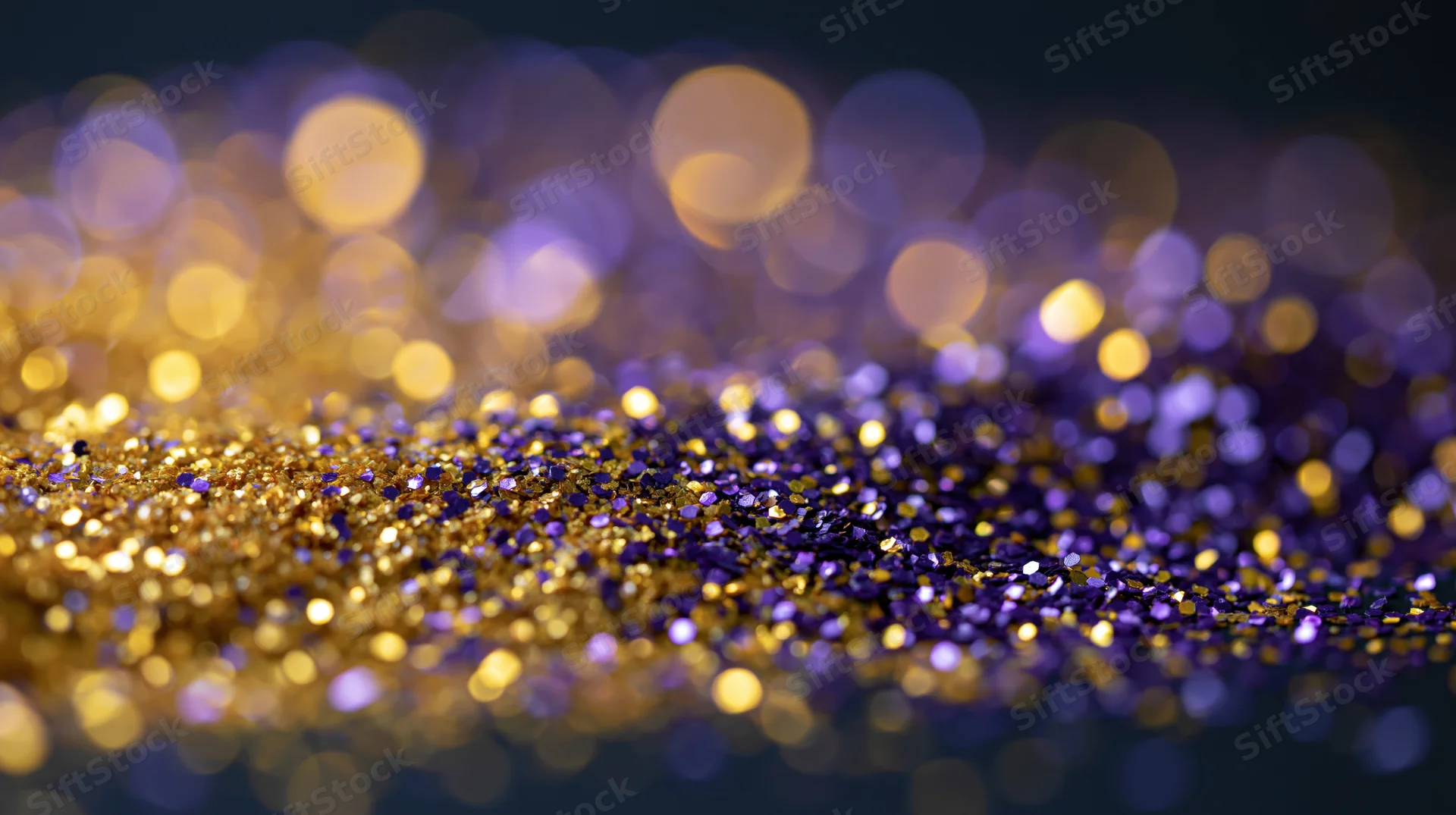 Gold and purple glitter scattered across a dark surface with bokeh lights in the background