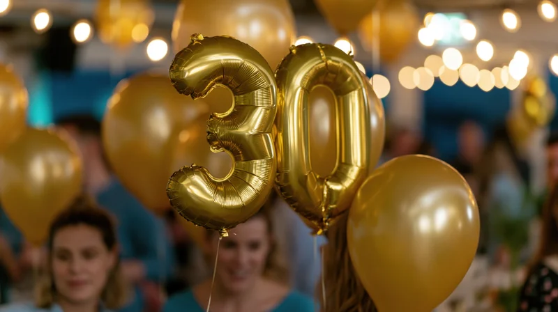 Gold foil number 30 balloons floating at a birthday party with guests in the background