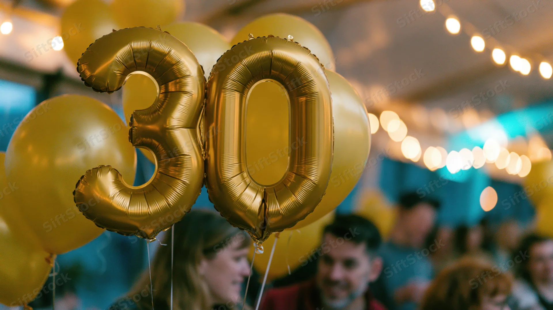 Gold foil number 30 balloons floating at a birthday party with people in the background
