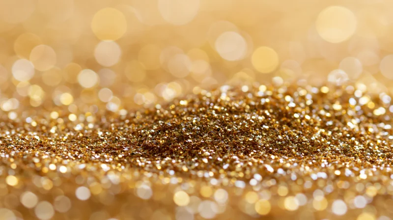 Gold glitter scattered across a flat surface with bokeh background