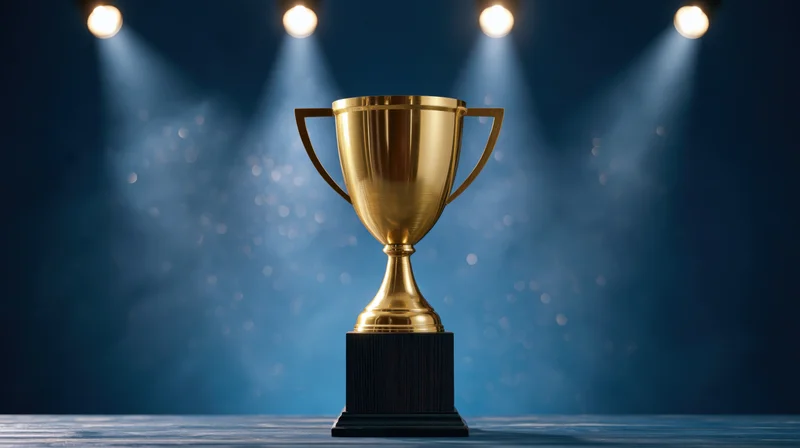 Golden trophy on a dark pedestal under spotlights on stage