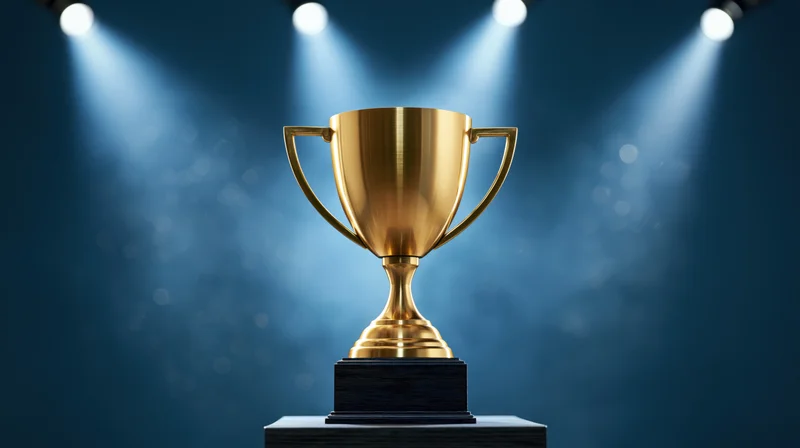 Gold trophy on dark wooden pedestal under spotlights on stage