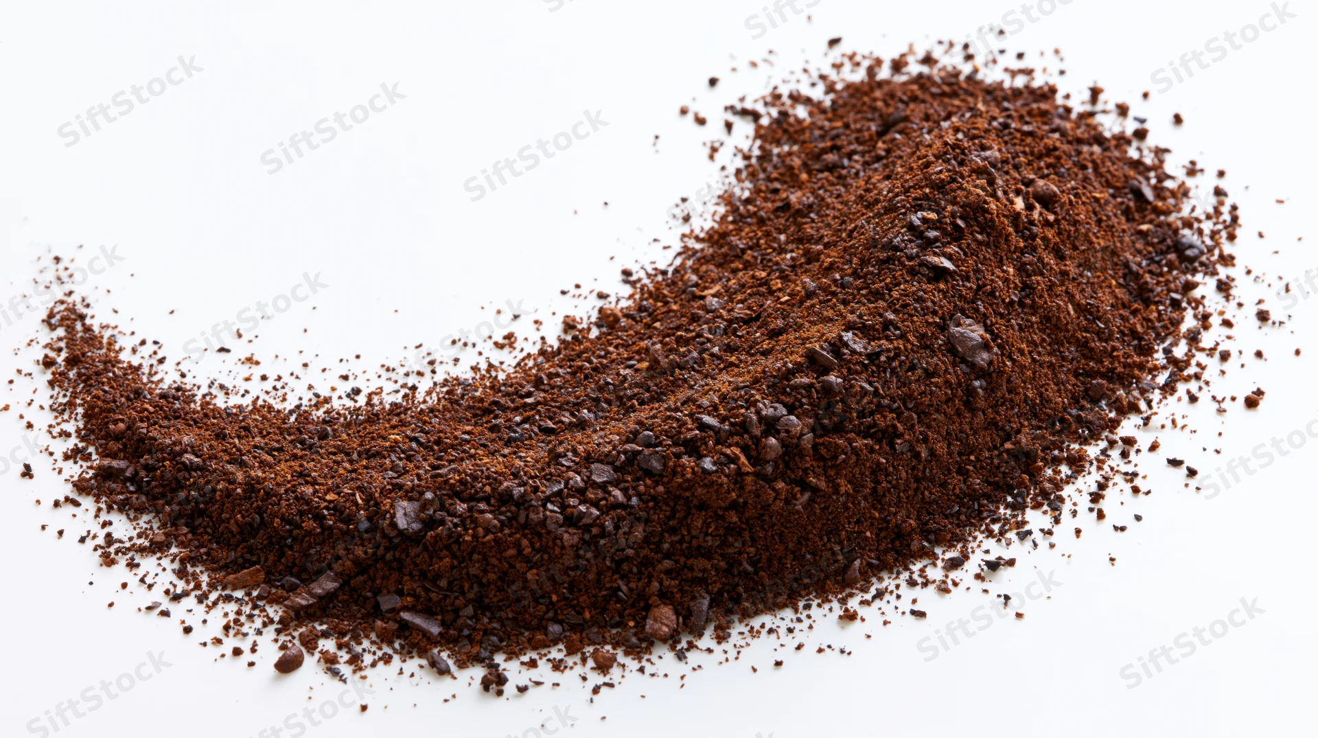 Ground coffee particles and coarse bean fragments scattered in a pile on white background
