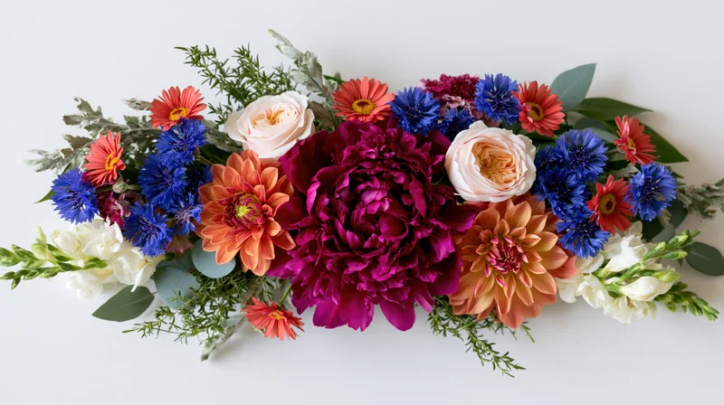 Horizontal floral arrangement with dahlias, peonies, roses, and greenery on white background