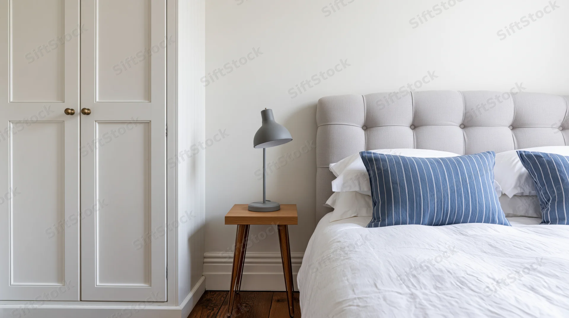 Minimalist bedroom corner with tufted upholstered headboard and bedside table beside a wardrobe