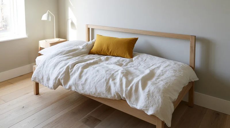 Minimalist bedroom with light oak wood bed frame and white bedding near a window