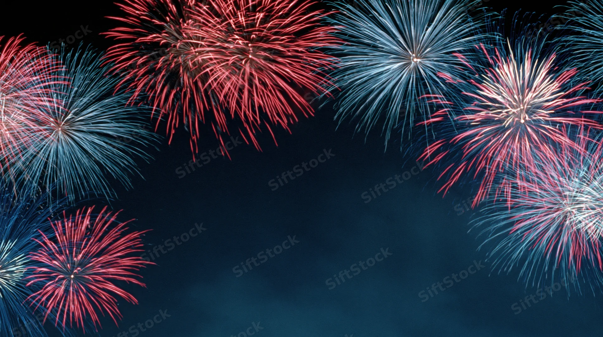 Red, white and blue fireworks bursting across a dark night sky with copyspace below