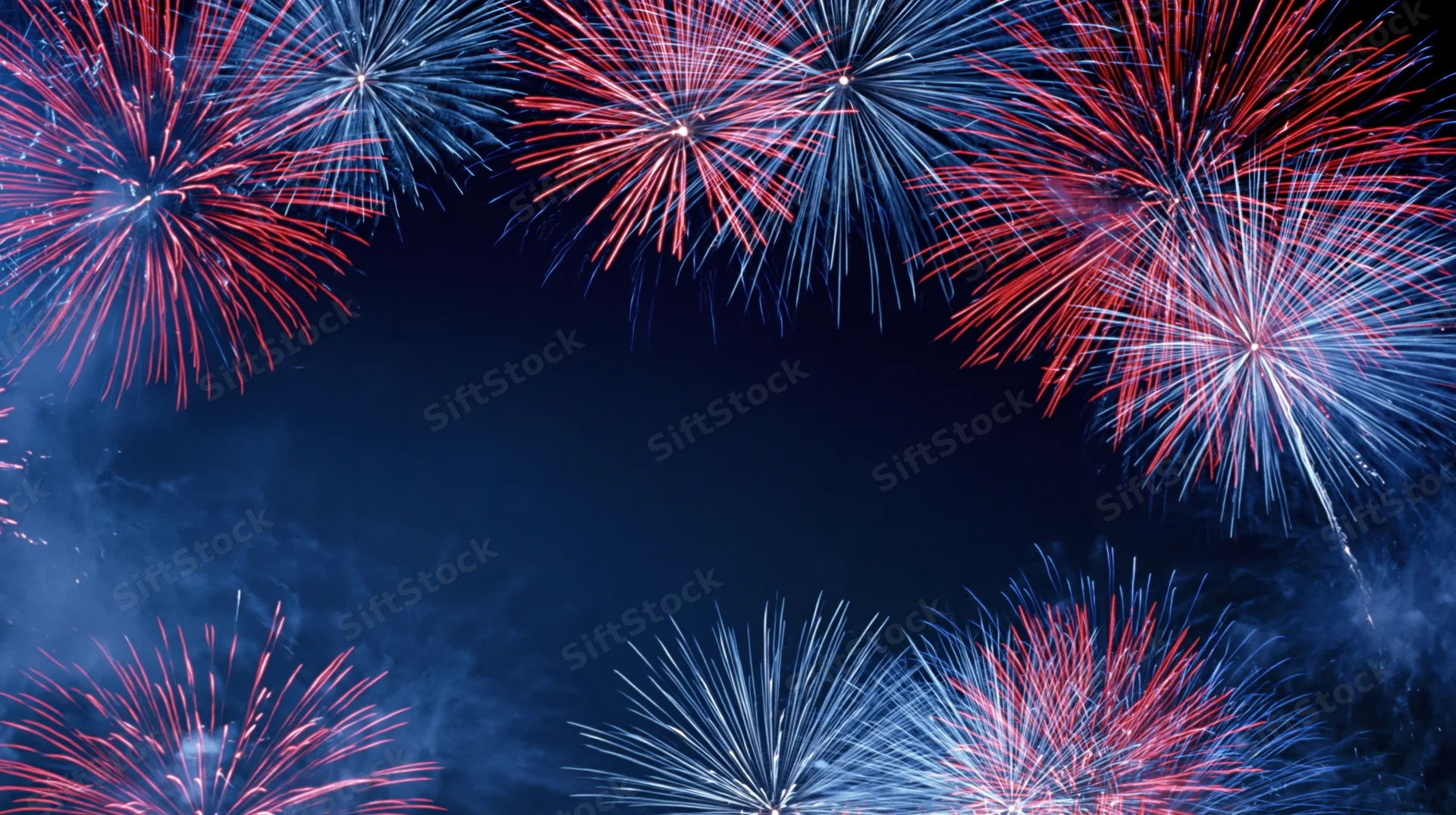 Fireworks bursting in red blue and white across night sky forming frame with central copyspace