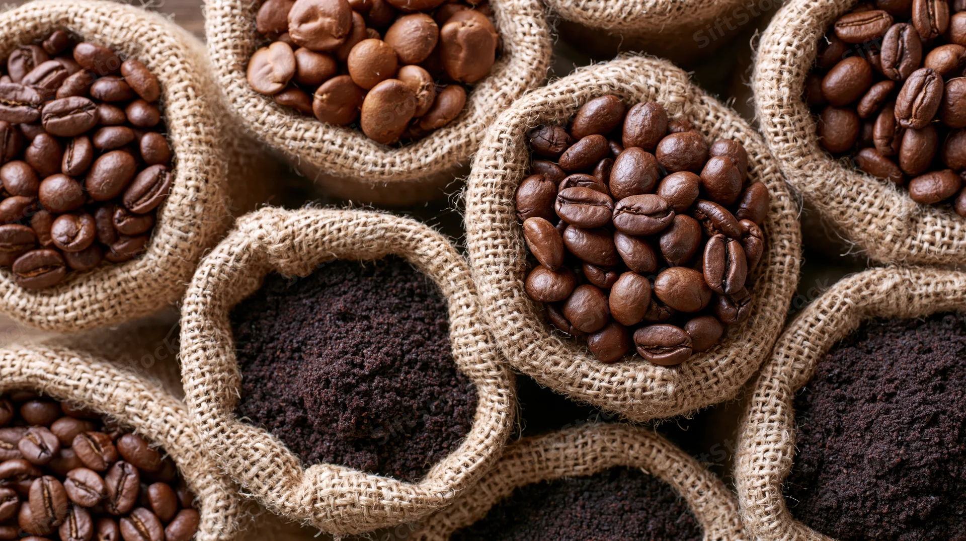 Roasted coffee beans and ground coffee in small burlap sacks arranged in a pattern