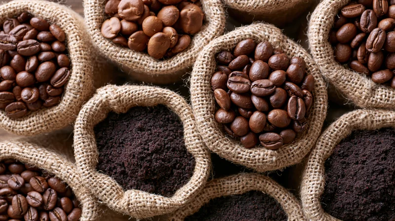 Roasted coffee beans and ground coffee in small burlap sacks arranged in a pattern