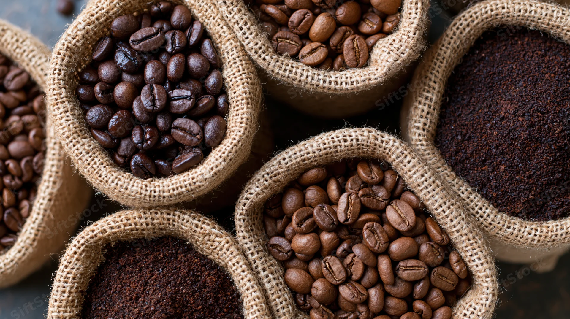 Roasted coffee beans and ground coffee in small burlap sacks arranged in a top-down view