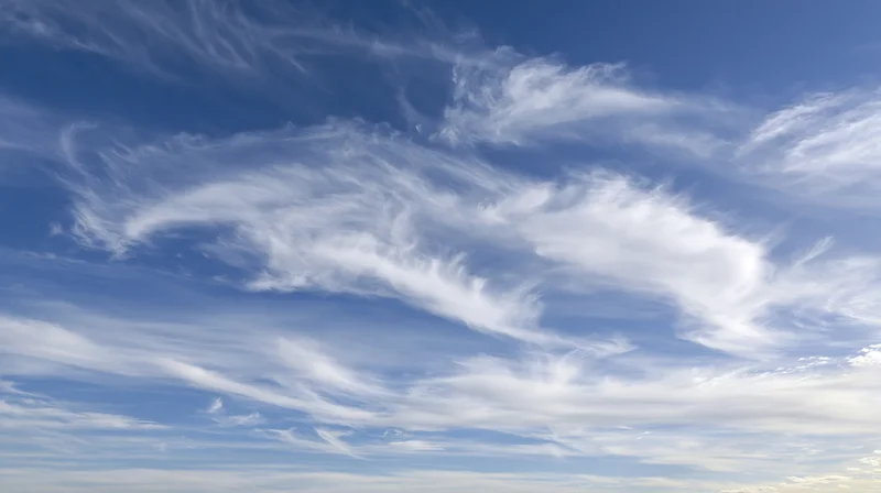 Blue sky filled with wispy cirrus clouds scattered across the horizon