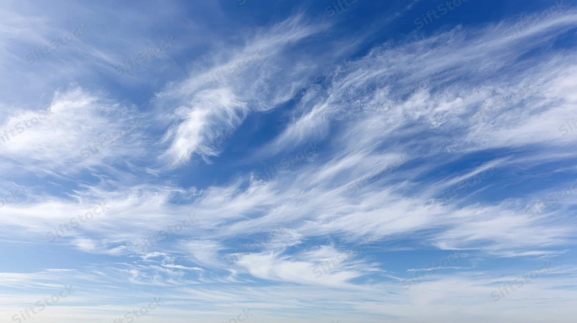 Open blue sky filled with wispy cirrus clouds scattered across the horizon