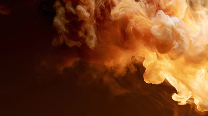 Swirling orange and cream ink dispersing in water against dark background