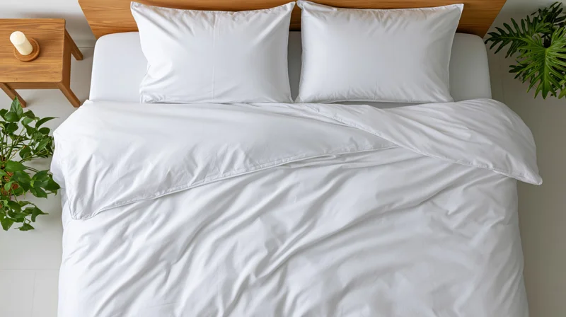 Overhead view of a neatly made double bed with white bedding and green plants beside it