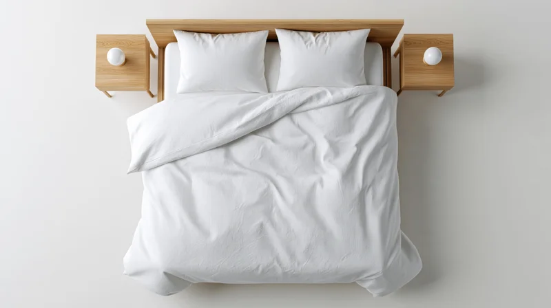 Overhead view of a neatly made double bed with white bedding and wooden furniture in a minimalist bedroom