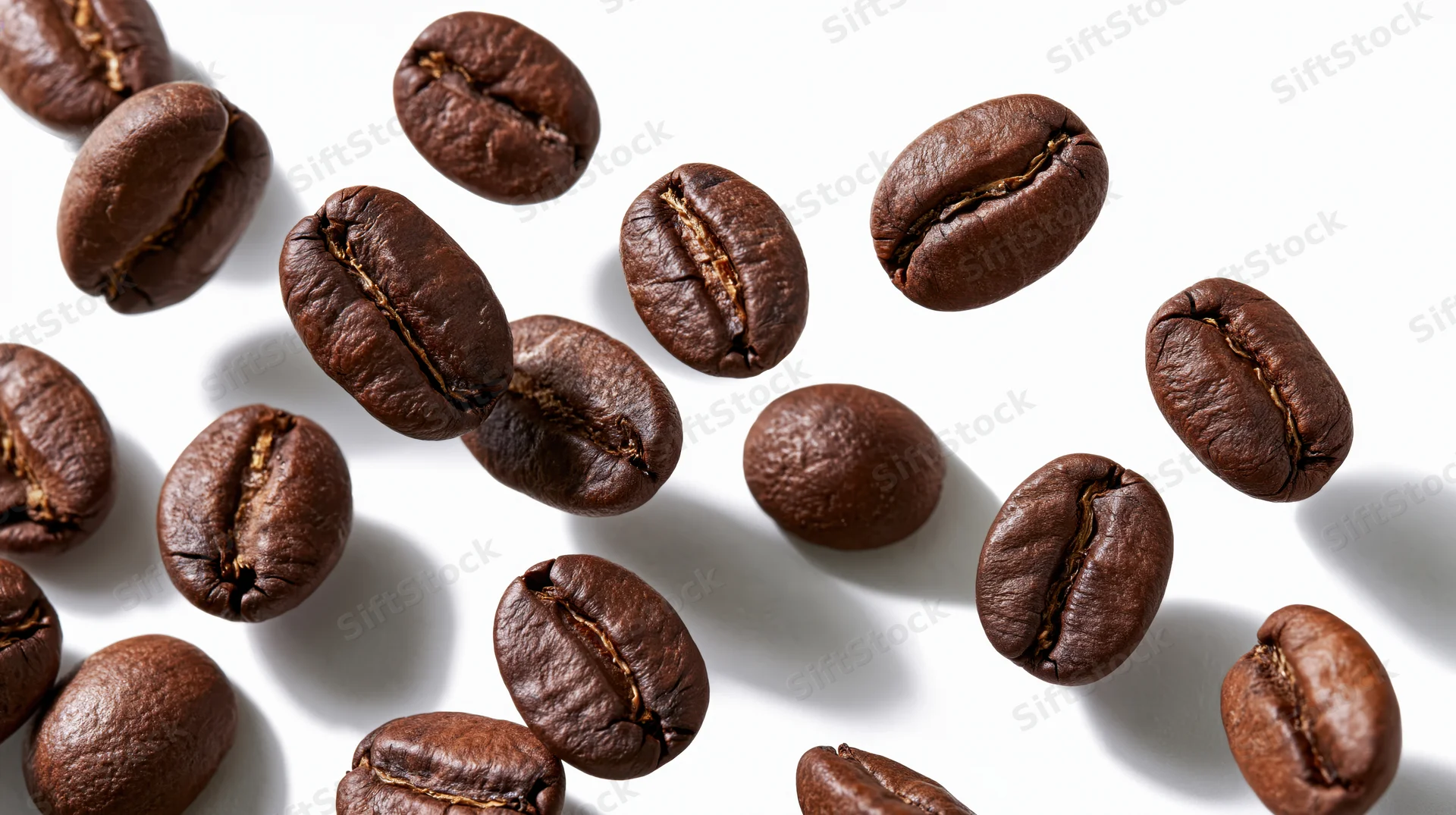 Roasted coffee beans falling midair against a white background