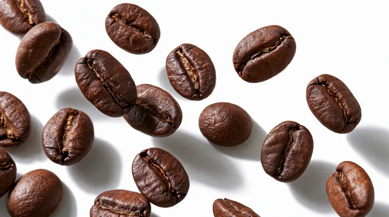 Roasted coffee beans falling midair against a white background