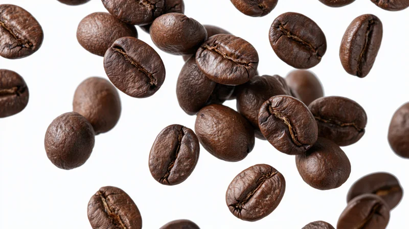 Roasted coffee beans falling midair against a white background