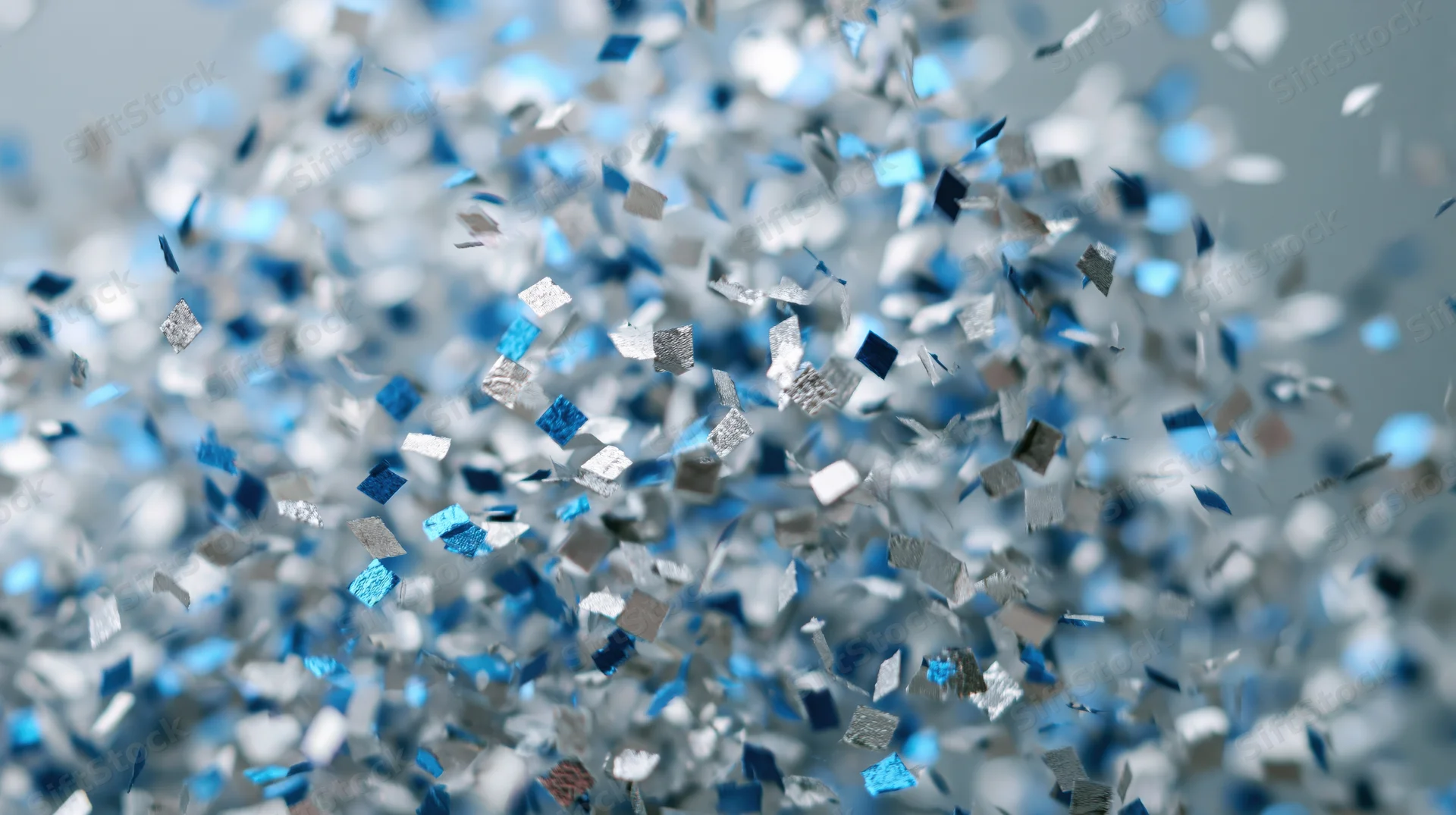 Metallic blue and silver confetti pieces floating mid-air in celebration