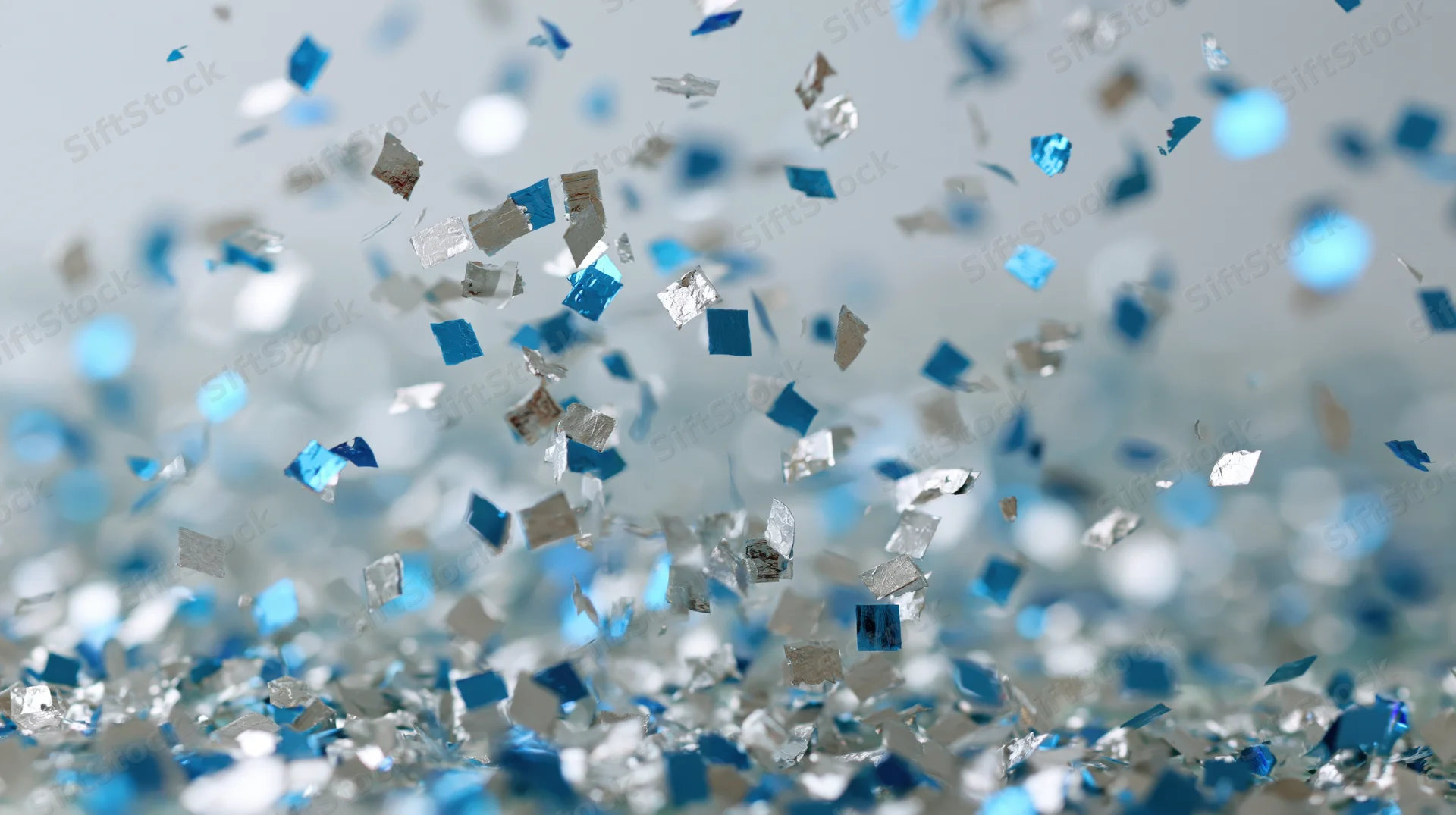 Blue and silver metallic confetti pieces floating mid-air in celebration