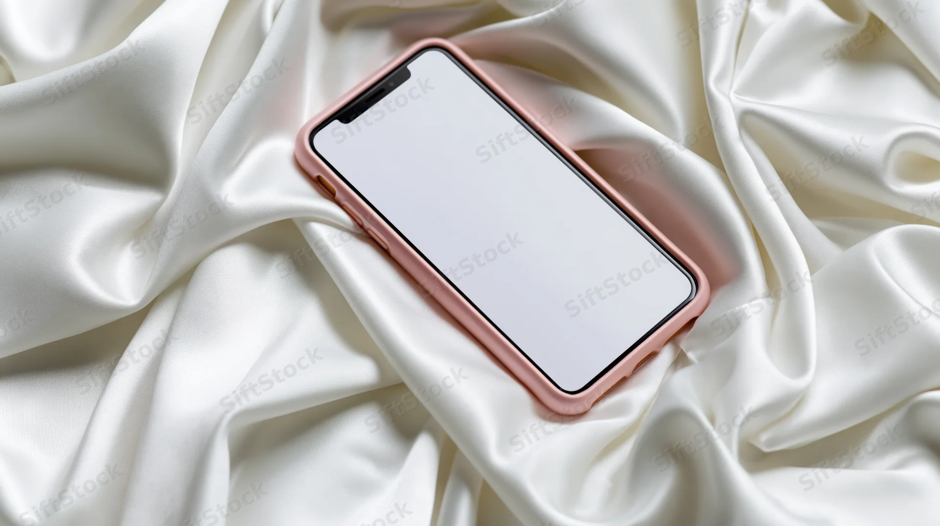 Smartphone with rose gold case resting on white silk fabric