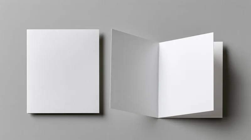 Two blank white square greeting cards, one folded and one open, on a neutral grey surface