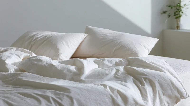 Unmade bed with white pillows and rumpled sheets in a bright bedroom
