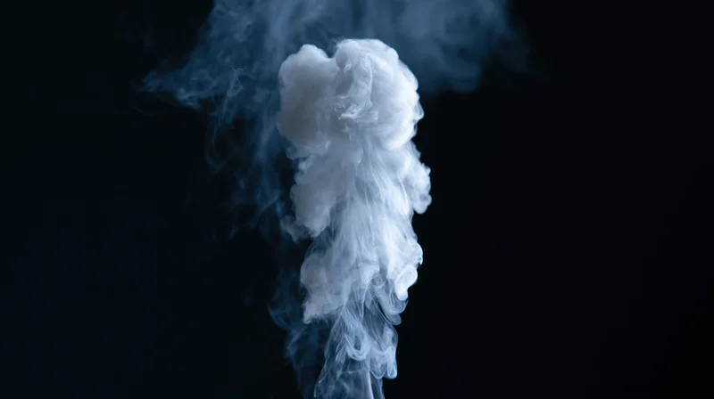 White smoke rising and curling upward against a black background