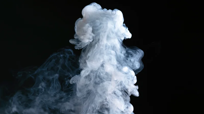 White smoke rising and curling upward against a black background