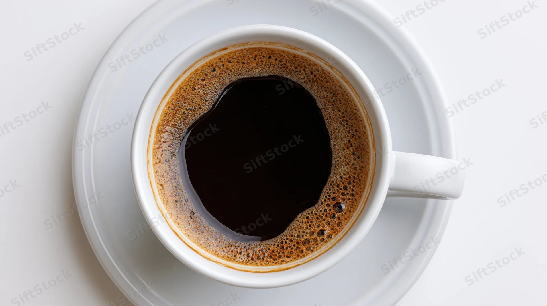 White ceramic coffee cup filled with black coffee on saucer viewed from above on plain surface