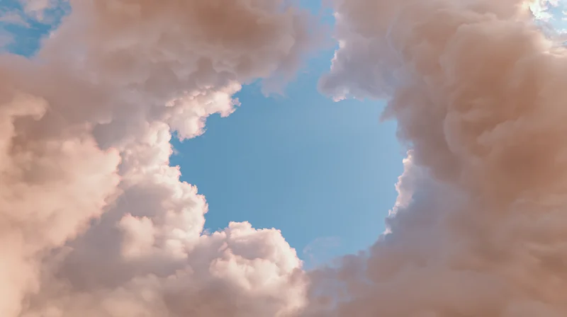 Sky with fluffy pink and white clouds framing a clear blue opening above