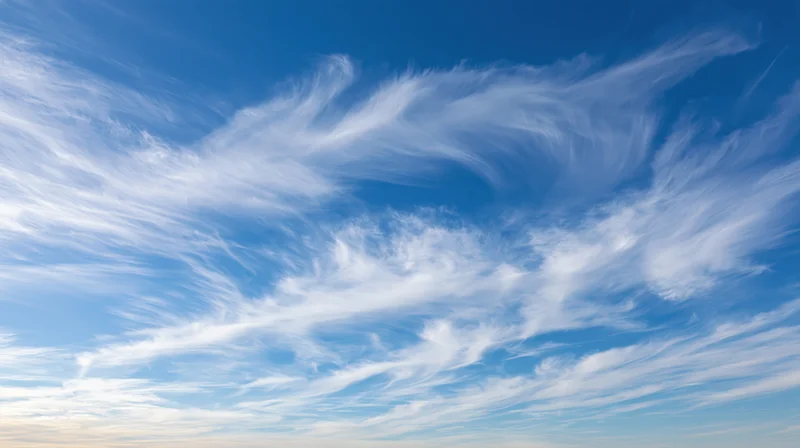 Wide upward view of open daytime sky filled with wispy white clouds against blue background