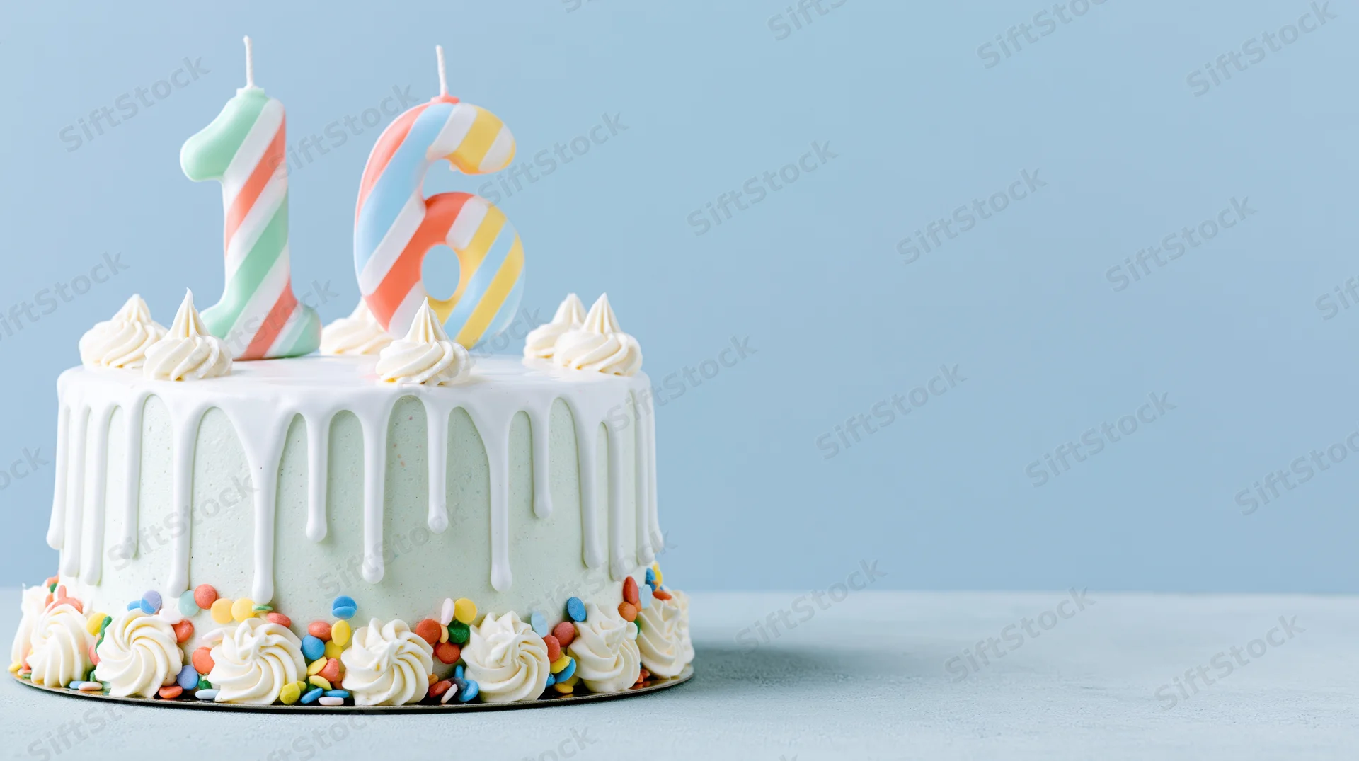 Birthday cake with number 16 candles and white drip frosting on light blue surface