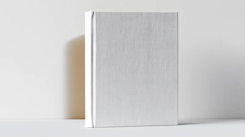 Blank white hardcover book standing upright against a plain wall with soft shadow and copyspace on either side