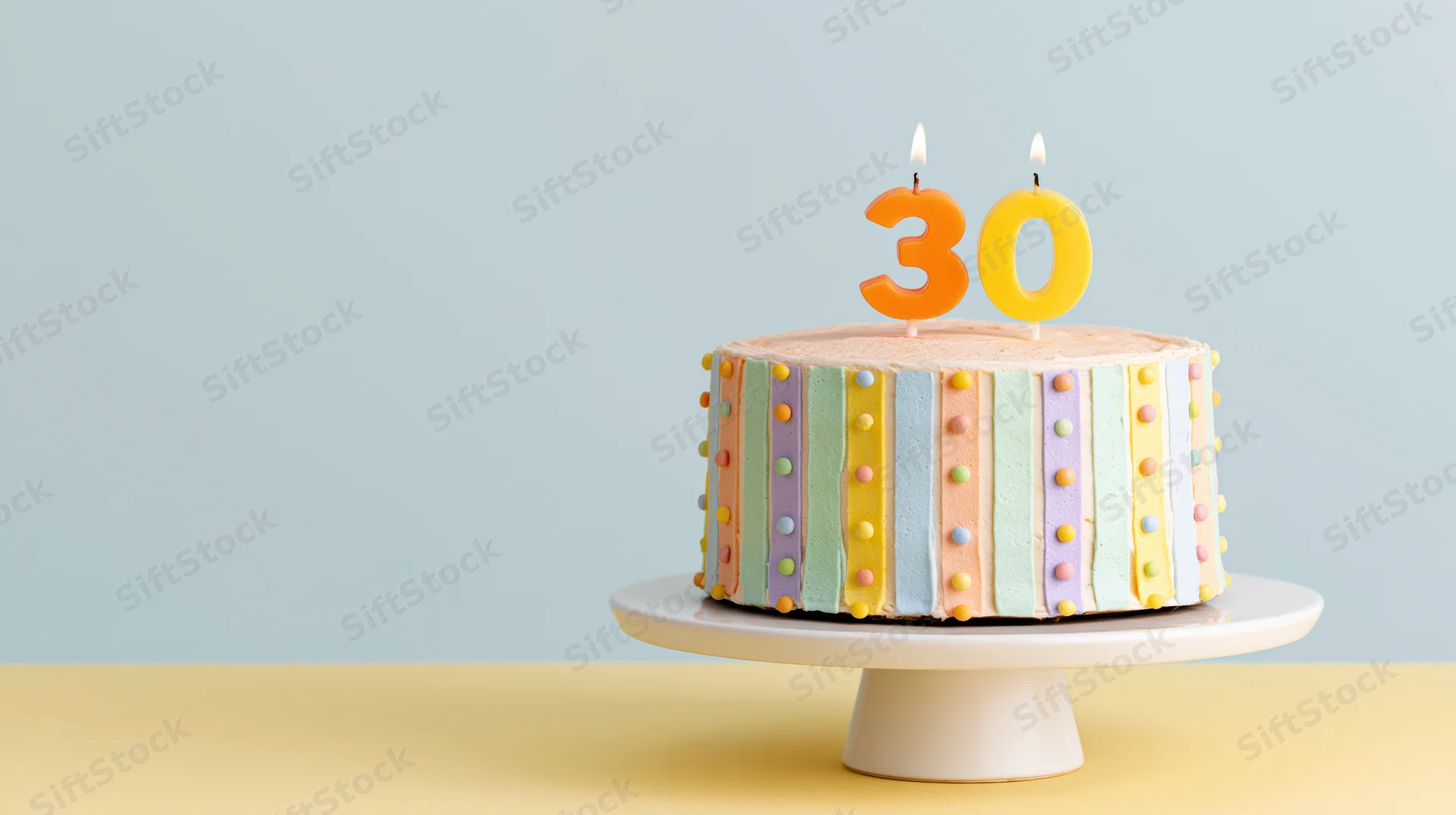 Decorated birthday cake with number thirty candles on white pedestal stand