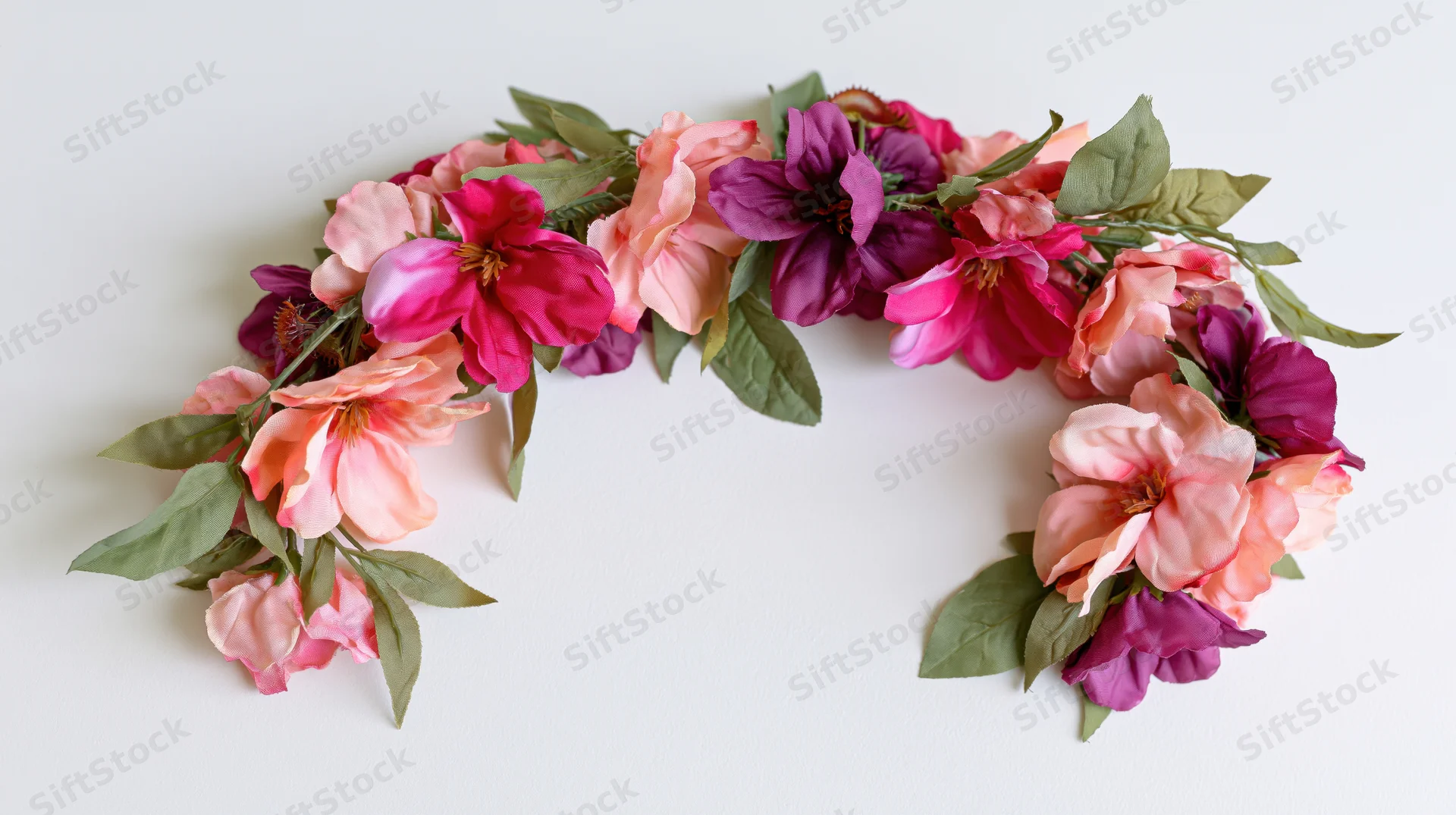Floral garland arranged in an arch shape on a white surface