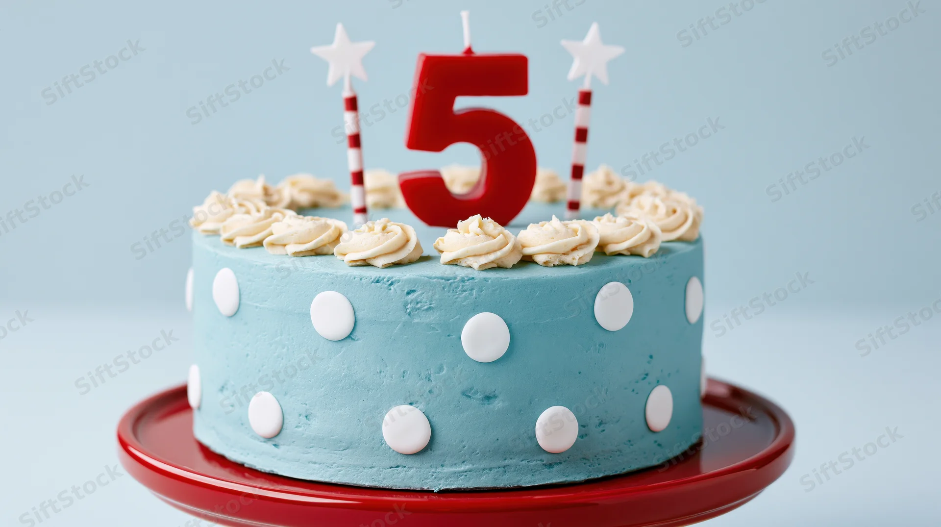 Light blue polka dot birthday cake with number five candle and star candles on red plate