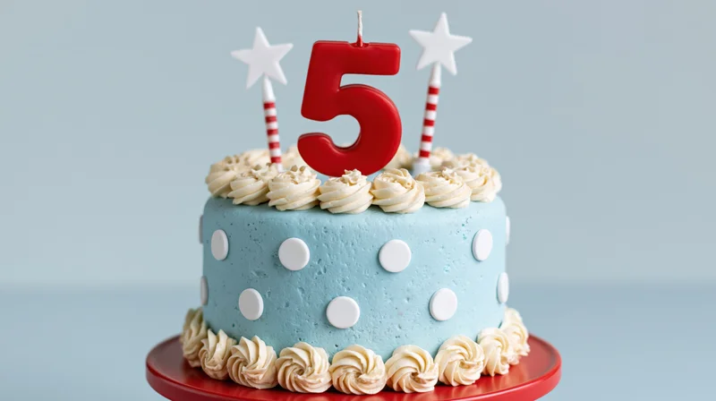 Light blue polka dot cake with red number five candle and star candles on red stand